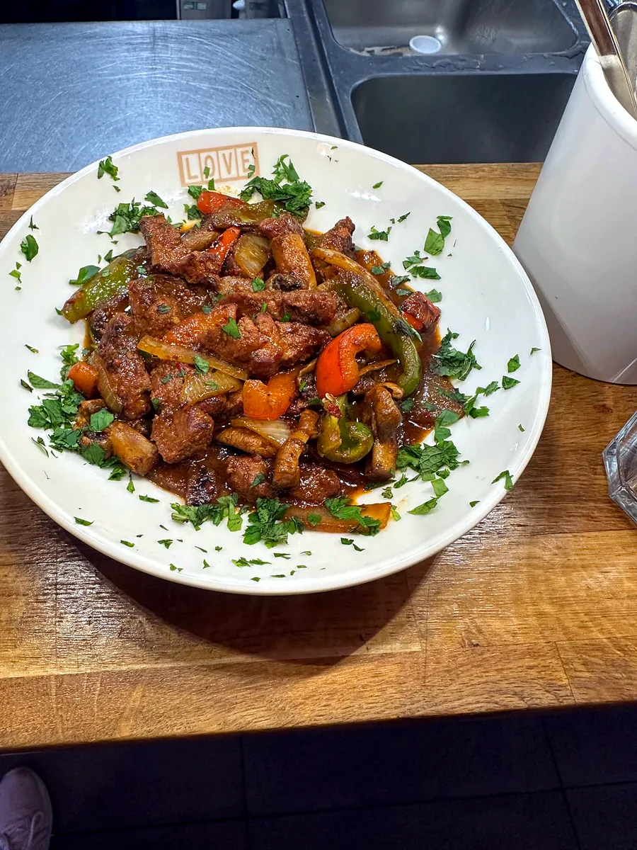 A rich dish of meat with peppers, onion and fresh parsley in a Love Dulwich bowl