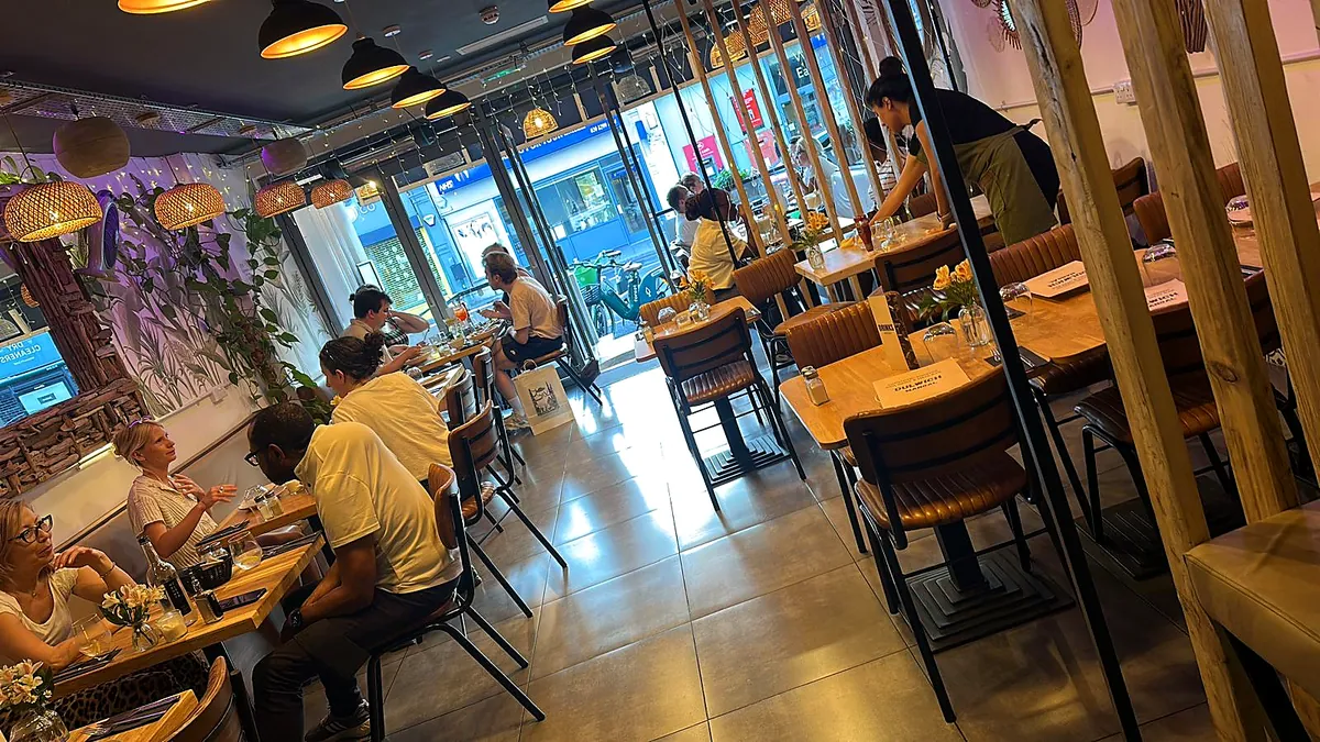 The Love Dulwich dining room in daylight, with wooden tables and rattan lamps