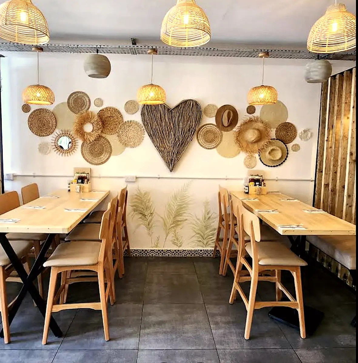 Inside Love Dulwich: woven wall baskets around a heart, light wood tables and rattan pendant lamps