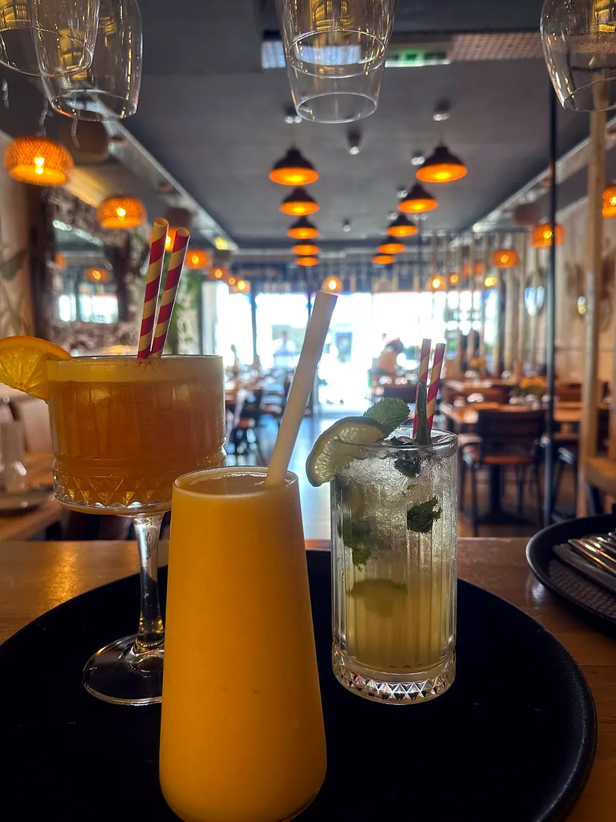 A mango drink, a mojito and an orange cocktail on a tray in the dining room
