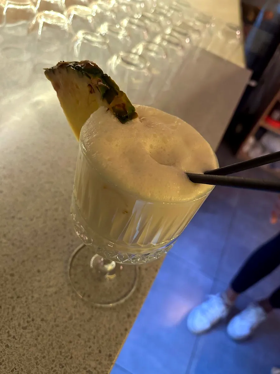 A piña colada with a pineapple wedge on the bar
