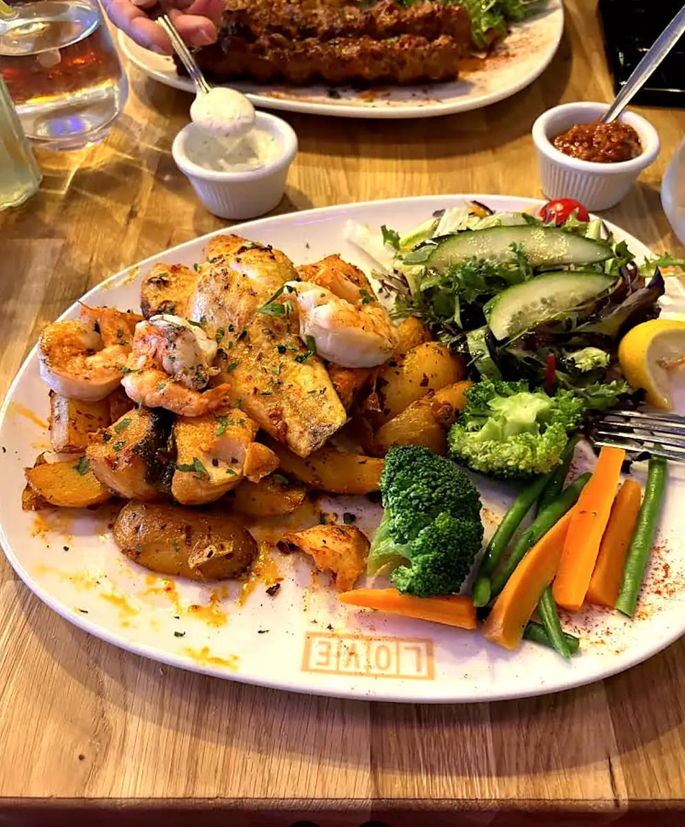 Grilled seafood plate with prawns, salmon and sea bass, sautéed potatoes and vegetables