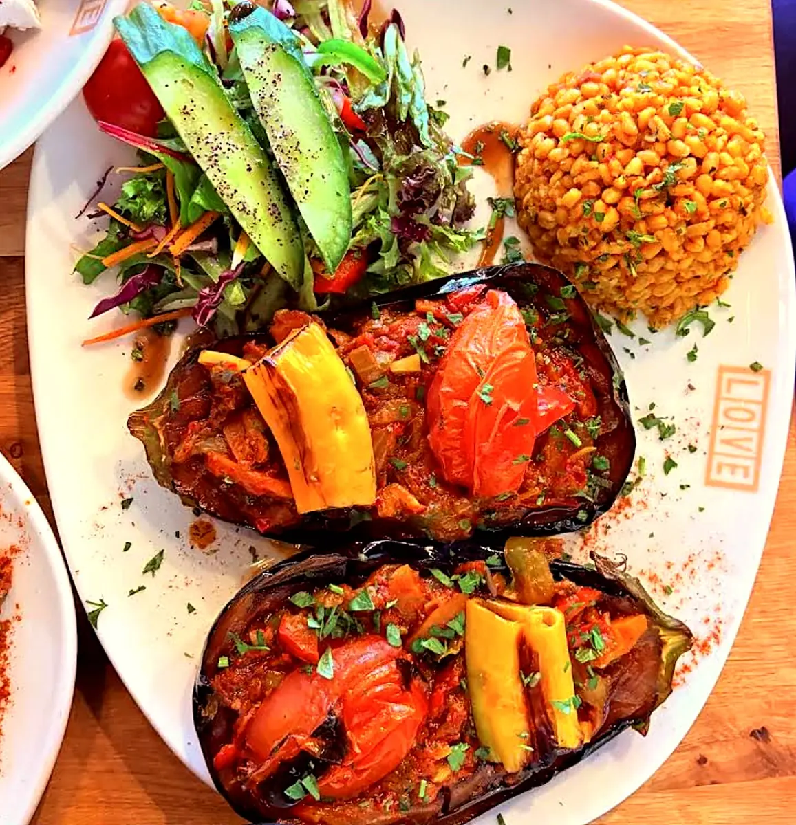 Stuffed aubergines with tomato and peppers beside bulgur rice and salad